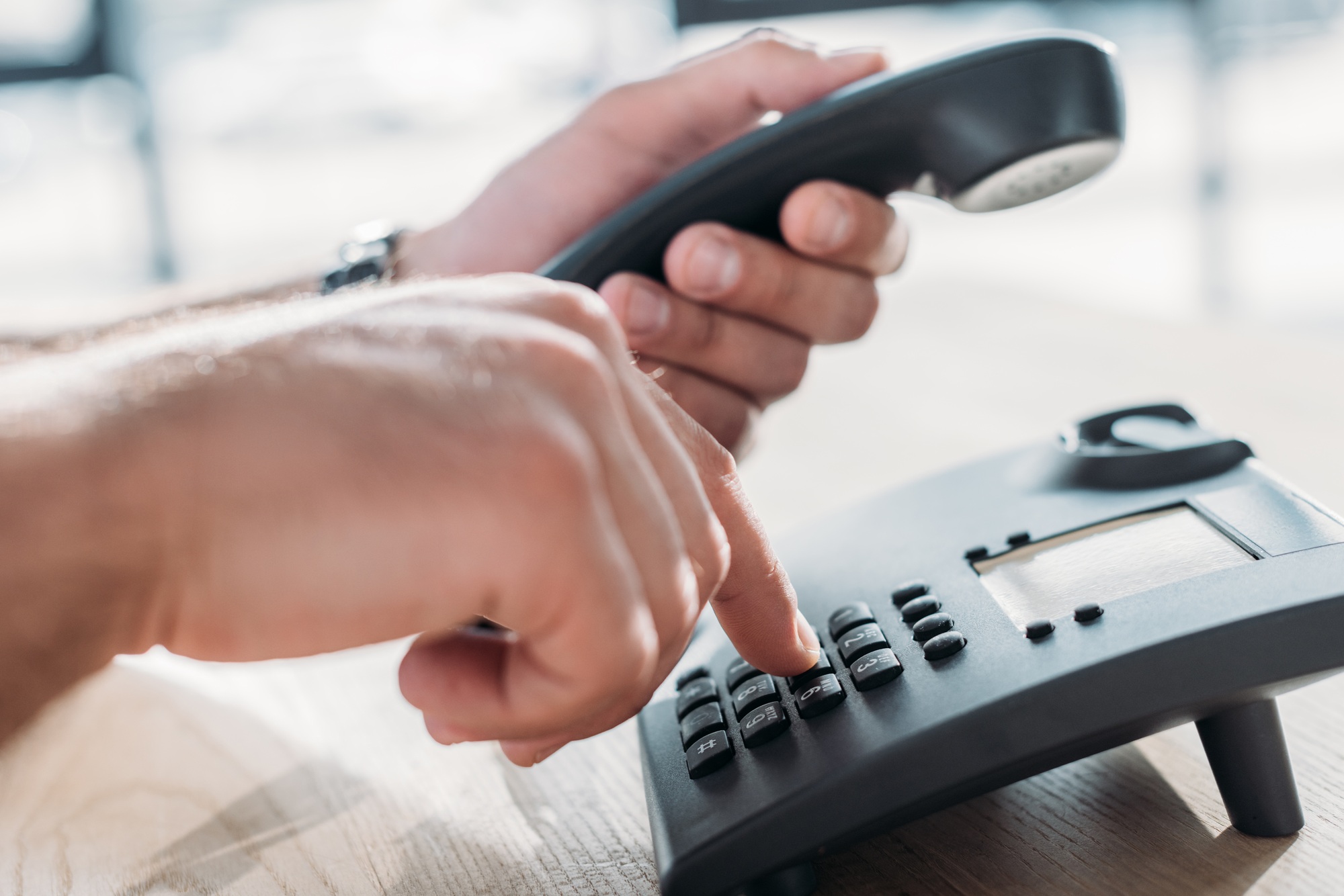 cropped shot of man making dialing stationary phone to make call